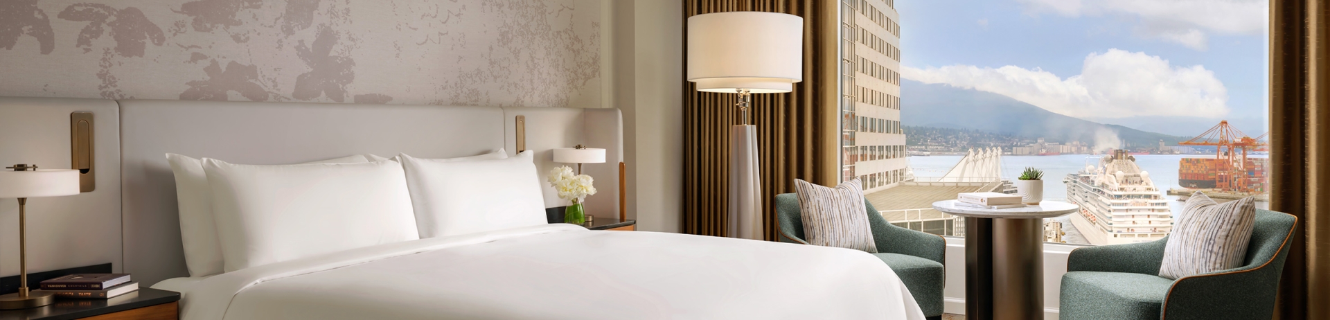 Newly renovated guestroom at Fairmont Waterfront featuring modern coastal design, king bed, and expansive harbour views through floor-to-ceiling windows, showcasing Vancouver’s waterfront and natural light-filled interiors.
