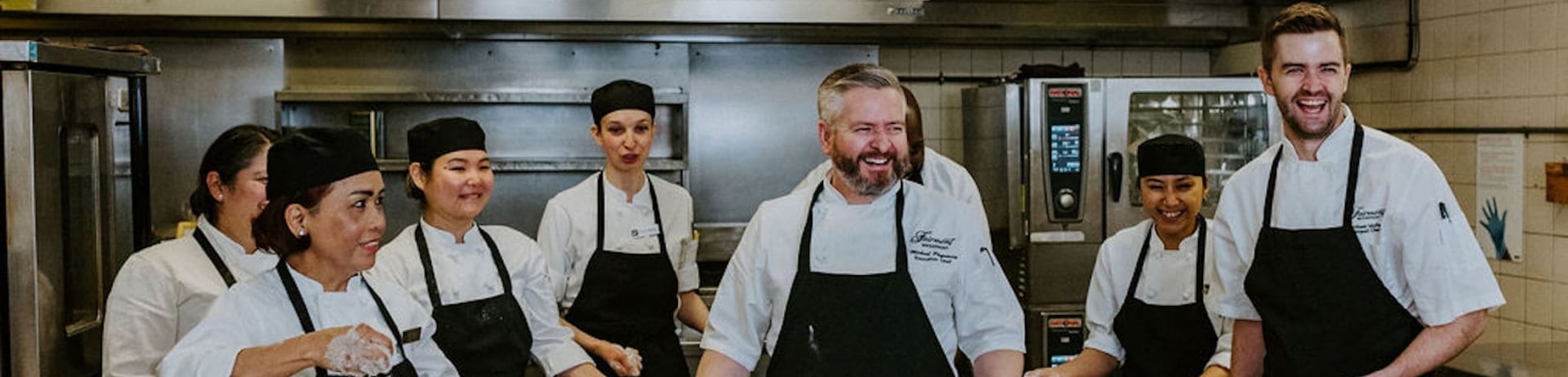 A kitchen team preparing food around a metal table