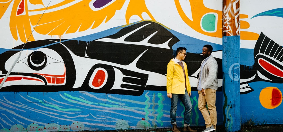 Two men chatting in front of a graffiti wall