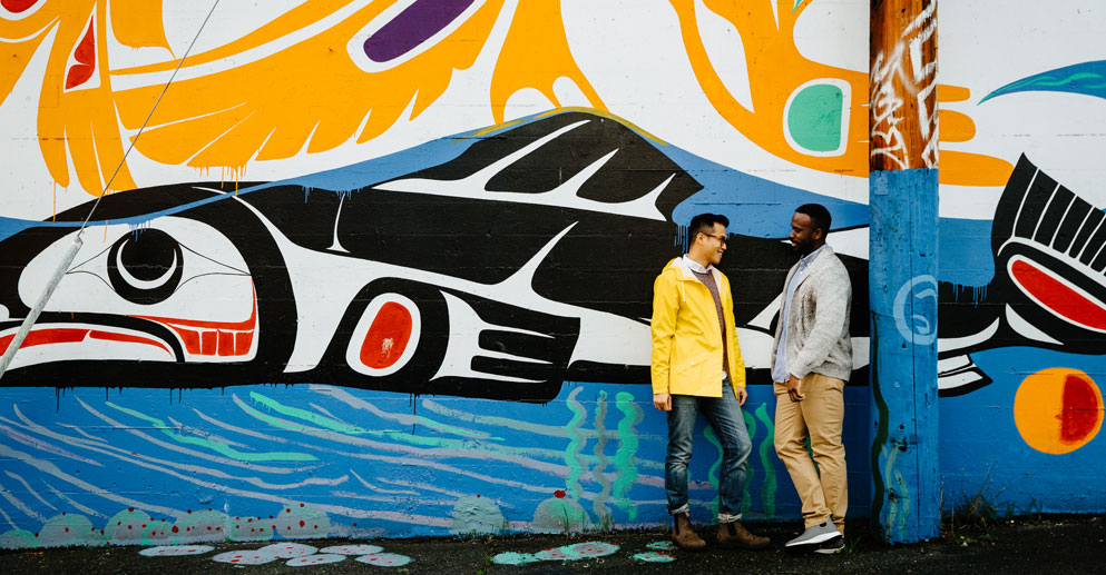 Two men chatting in front of a graffiti wall