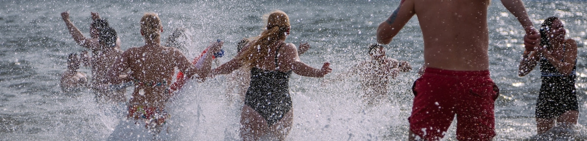 A group of people running into the ocean.