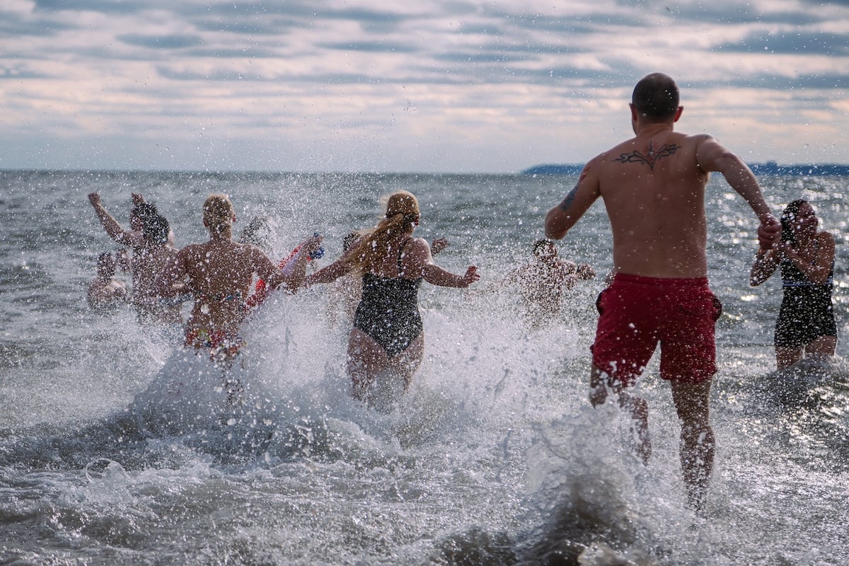 A group of people running into the ocean.