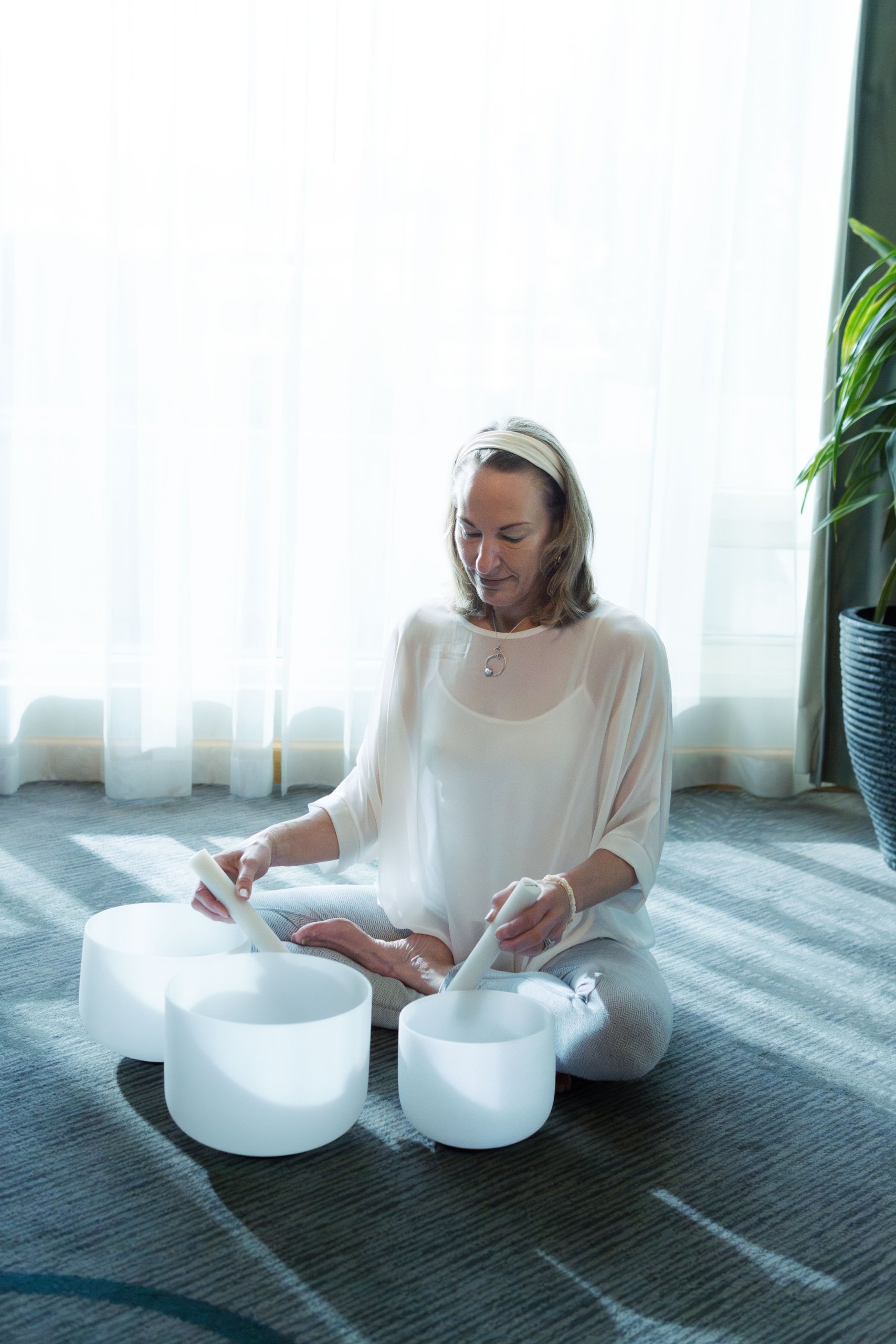 instrutor sitting cross-legged with crystal sound bowls in front of her.