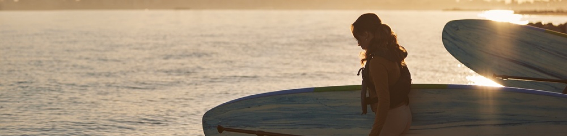 Woman with paddleboard at sunset on Kits Beach