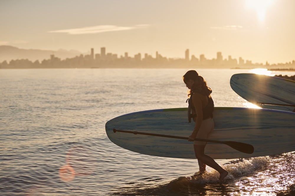 Woman with paddleboard at sunset on Kits Beach