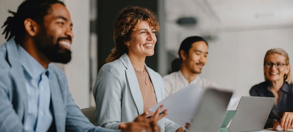 A group of people sitting at boardroom table in a meeting.