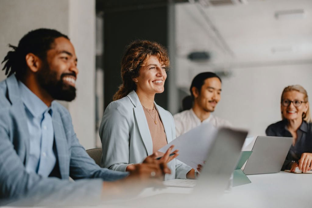 A group of people sitting at boardroom table in a meeting.