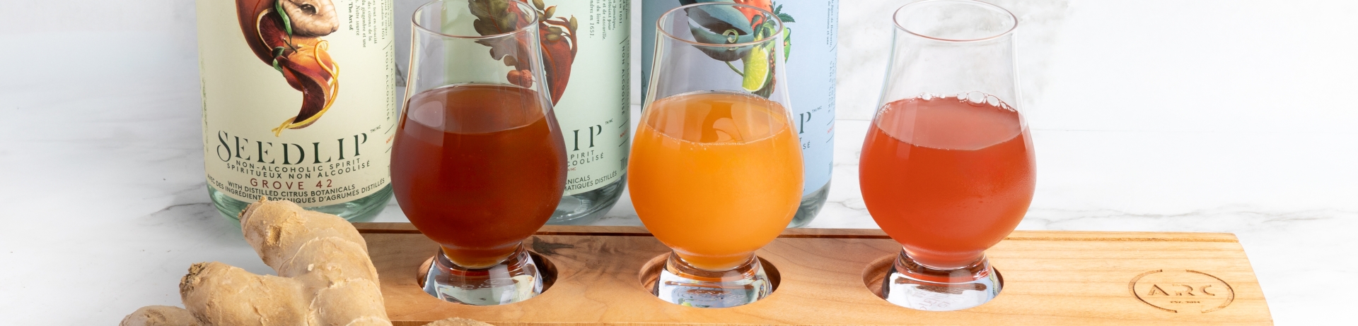 A flight if spirit-free cocktails with bottles of Seedlip set behind and fresh ingredients in front.