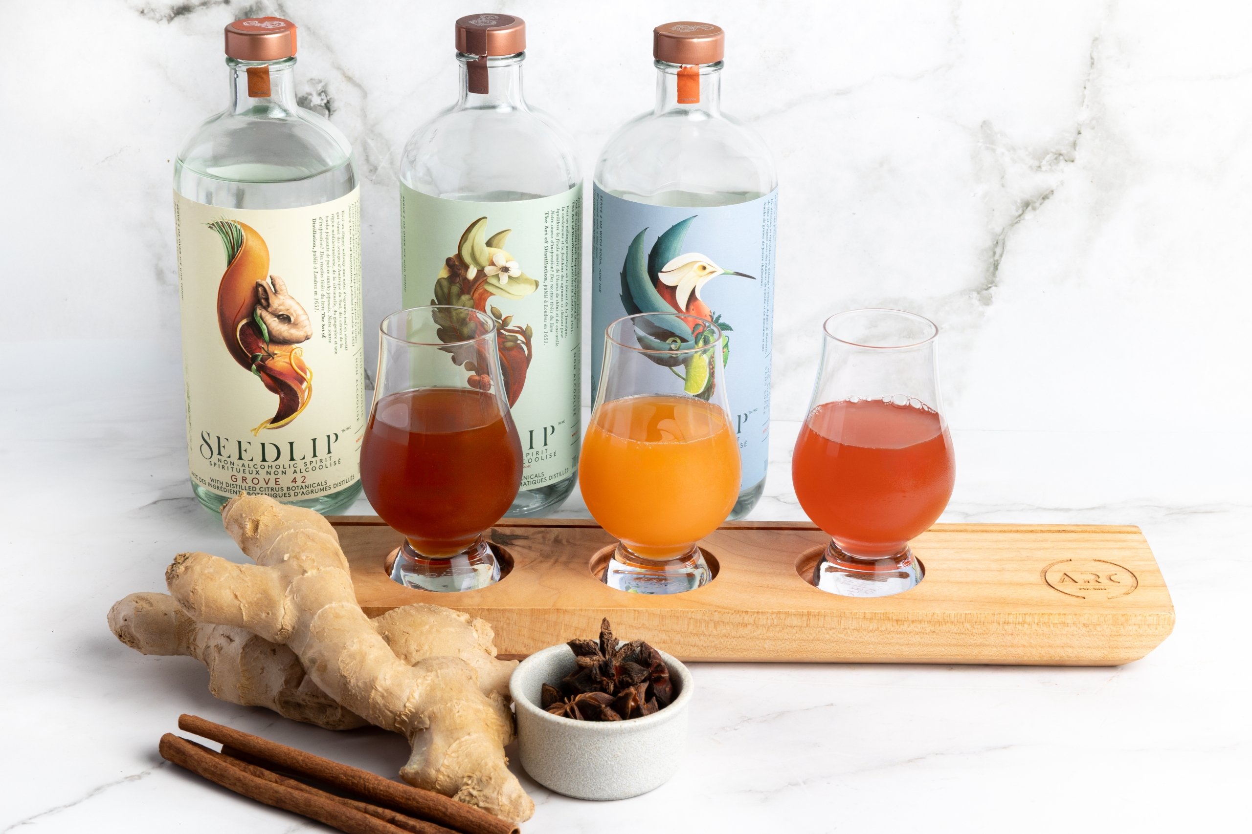 A flight if spirit-free cocktails with bottles of Seedlip set behind and fresh ingredients in front.