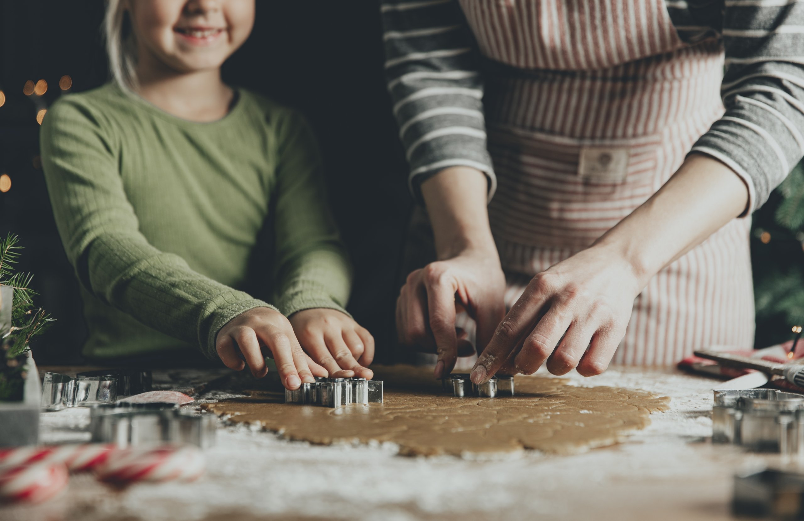 Merry Christmas, Happy New Year. Gingerbread cooking, baking. Mom and daughter make cookies, cut out different shapes of cookies using cutting metal mold on wooden table at kitchen. High quality photo