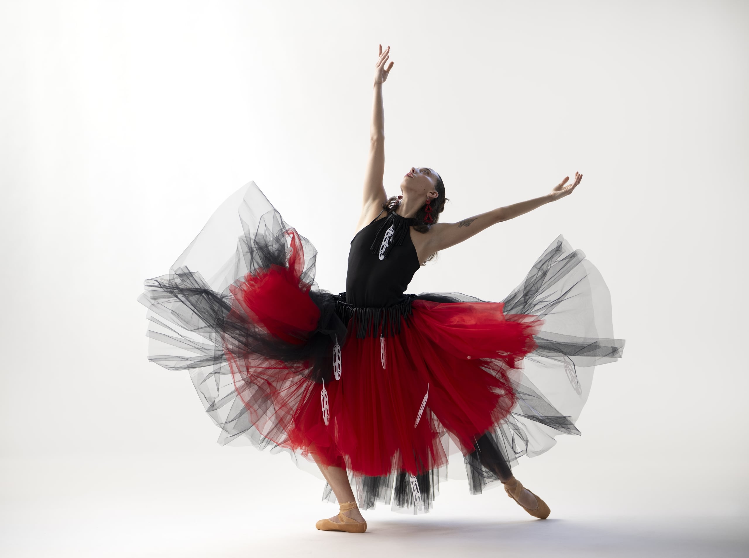 Ballet BC dancer in ballet pose with white background, showcasing a design by Yolonda Skelton Jackson – Indigenous artist and fashion designer – of the Gitxsan Nation.