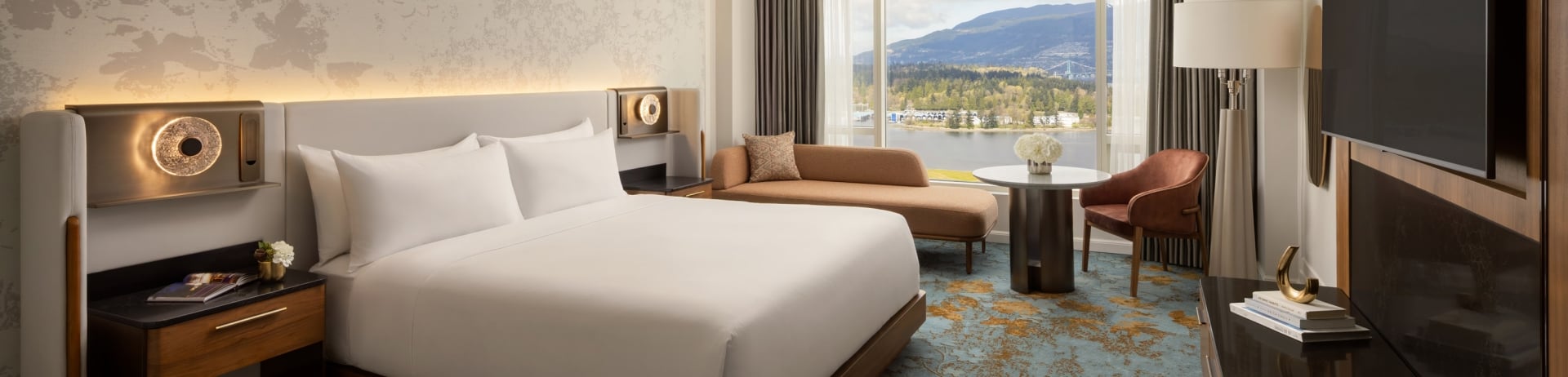 Newly renovated guestroom at Fairmont Waterfront featuring modern coastal design, king bed, and expansive harbour views through floor-to-ceiling windows, showcasing Vancouver’s waterfront and natural light-filled interiors.